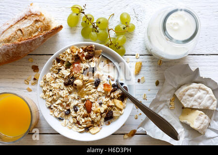 Gesundes Frühstück mit Müsli, Trauben, Käse und Saft auf rustikalen weißen Tisch von oben. Stockfoto