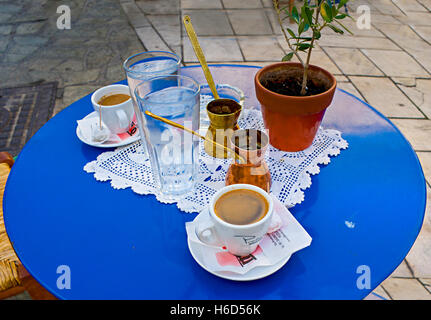 Zwei Kaffeetassen, Cezve (Kaffeekannen), Gläser mit kaltem Wasser, kleine Hand gemachte Tischdecken auf den blauen Tabl serviert werden Stockfoto