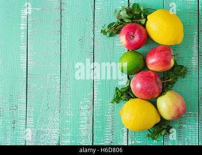 Reife Früchte (Äpfel, Zitronen und Limetten) auf einem hellen Hintergrund aus Holz. Ansicht von oben Stockfoto