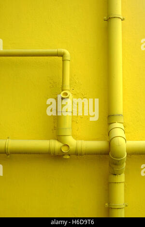 Gelbe Wand von Gebäude- und Wasserleitungen Stockfoto