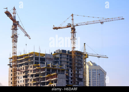Bau von Kränen und im Bau Gebäude gegen den klaren Himmel Stockfoto