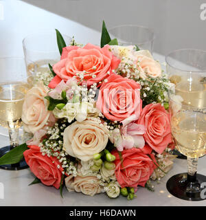 Schöner Blumenstrauß aus Rosen in einem Umfeld von fünf Gläser mit Champagner Stockfoto
