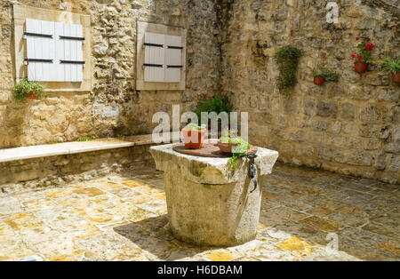 Die mittelalterlichen Unentschieden-Brunnen können heutzutage als Tisch oder eine Stütze für Blumen in den improvisierten Gärten, Budva, Montenegro verwendet werden. Stockfoto