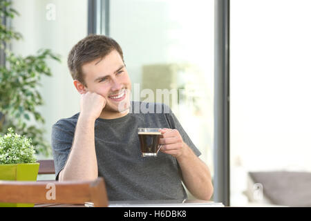 Gut aussehender Mann, entspannend, trinken Kaffee sitzen in einer Tabelle in einen Balkon von einem Hotelzimmer oder zu Hause Stockfoto