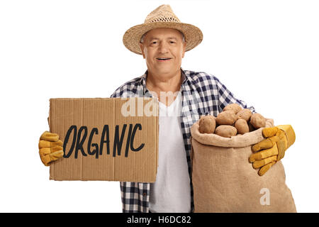 Älterer Bauer hält einem Leinensack voller Kartoffeln und ein Pappschild, das sagt Bio isolierten auf weißen Hintergrund Stockfoto