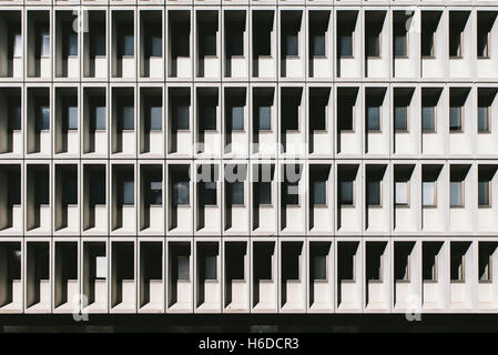 mehrere kleine weiße Quadrat gleich symmetrische Windows auf ein Bürogebäude mit Schatten. Wände sind weiß mit Linien-Muster Stockfoto
