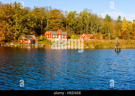 Jarnavik, Schweden - 25. Oktober 2016: Ökologische Dokumentation der Küste leben. Rotes Holzhaus in bunten Herbst-Landschaft auf Stockfoto