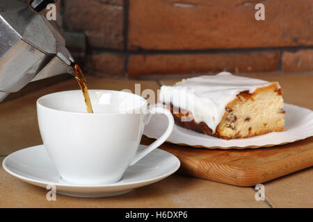 Gießen Sie Kaffee in die Tasse und Käsekuchen. Frühstück. Stockfoto