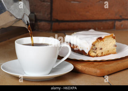 Gießen Sie Kaffee in die Tasse und Käsekuchen. Frühstück. Stockfoto