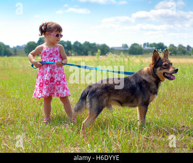 Kleines Mädchen mit Hund auf der Wiese und den Hund an der Leine zu halten Stockfoto