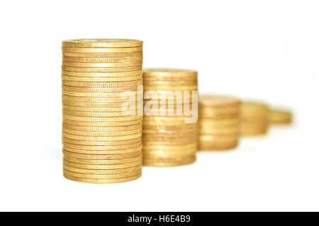 Wirtschaftliche Konzepte. Goldene Münzen auf weißem Hintergrund. Münzen, die auf einander gestapelt sind. Makro. Konzentrieren Sie sich auf den ersten Haufen Münzen. Stockfoto