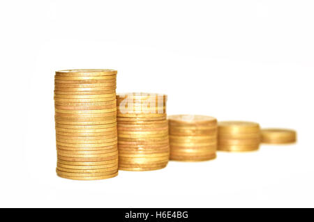 Wirtschaftliche Konzepte. Goldene Münzen auf weißem Hintergrund. Münzen, die auf einander gestapelt sind. Makro. Konzentrieren Sie sich auf den ersten Haufen Münzen. Stockfoto
