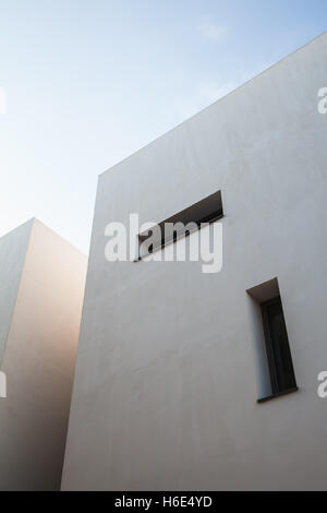 Abstrakt Architektur Fragment, weiße Wände mit kleinen Rechteck Windows unter blauem Himmel Stockfoto