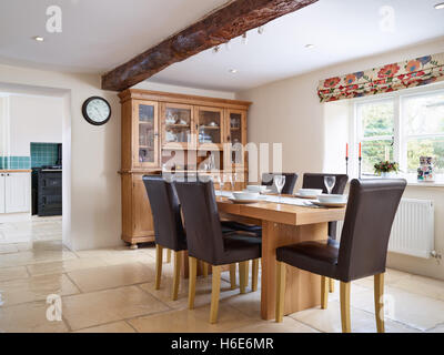 Ein Eichentisch set für 6 in einem großen Speisesaal, angrenzend an eine Küche in einem Landhaus in den Cotswolds, Gloucestershire, UK Stockfoto