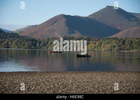 Ruhige herbstliche Szene in Keswick, Derwentwater, Cumbria, UK. Ein Kanufahrer paddeln sanft über den See in Richtung Ufer. Stockfoto