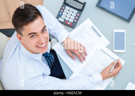 Porträt des jungen Büroangestellten Rezeption hautnah. Draufsicht der junge Mann am Tisch mit Stift und Dokumente. Stockfoto