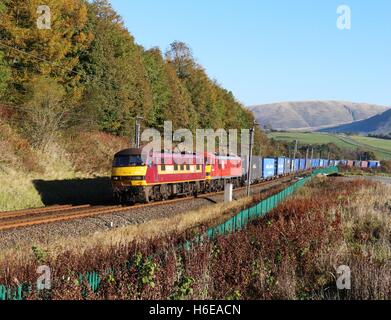 Zwei Klasse 90 e-Loks auf der West Coast Main Line in der Nähe von Beckfoot in Cumbria mit einem Güterzug von Containern. Stockfoto