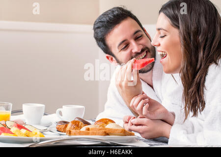 Großaufnahme Spaß Porträt des Paares im Bademantel auf Bett Frühstück zusammen. Stockfoto