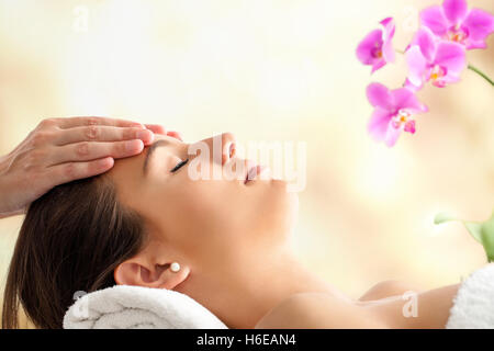 Porträt der jungen weiblichen Gesichts-Massage im Spa hautnah. Therapeuten massieren Frauenkopf vor hellen bunten Hintergrund. Stockfoto