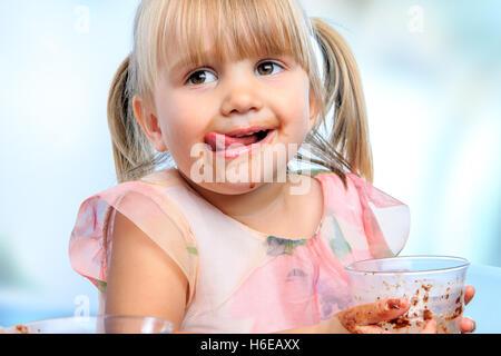 Porträt von kleinen Mädchen mit chaotisch Gesicht trinken Schokoladen Milchshake zu Hause hautnah. Stockfoto