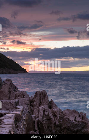 Sonnenuntergang und einem lila Himmel über der Adria in Trpanj Kroatien mit einer Langzeitbelichtung und Motion blur auf dem Wasser Stockfoto