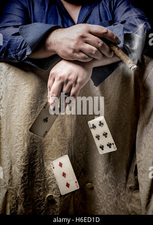 Mann, raucht eine Zigarre und Pokern mit fallenden Karten Stockfoto