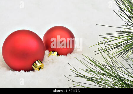 zwei rote Christbaumkugeln mit Tanne Zweige auf Schnee Hintergrund, Makro, Nähe, Raum für Text, horizontal, full-Frame Stockfoto