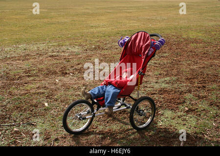 Babymädchen schläft im Kinderwagen draußen, an einem kalten Tag Stockfoto