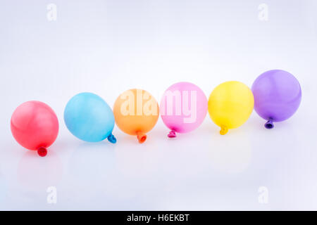 Bunte kleine Luftballons in Linie auf weißem Hintergrund Stockfoto
