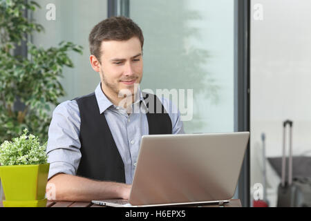 Exekutive arbeitet in einem Hotel im Freien auf dem Balkon während einer Geschäftsreise mit Koffern im Hintergrund Stockfoto