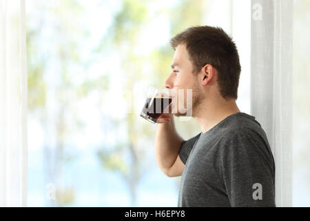 Seitenansicht eines Mannes trinken Kaffee Blick durch das Fenster des Hause oder im hotel Stockfoto