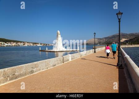 Mann und Frau zu Fuß über die Drapano Brücke vorbei an der Obelisk de Bosset in Argostoli auf der griechischen Insel Kefalonia Stockfoto