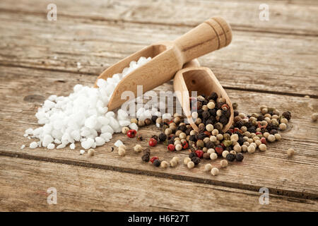 Große feinkörniges Salz und gemischte Pfefferkörner auf hölzernen Schaufeln, auf rustikalen Tisch Stockfoto