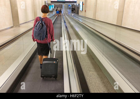 Eine Frau auf einem Travelator am Flughafen von Palma auf Mallorca. Stockfoto