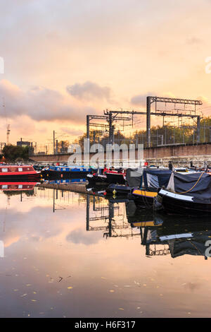 Goldener Herbst Licht bei Sonnenuntergang auf narrowboats in einem Becken auf der Regent's Canal durch die Eisenbahnlinie günstig aus St. Pancras International, London, UK Stockfoto