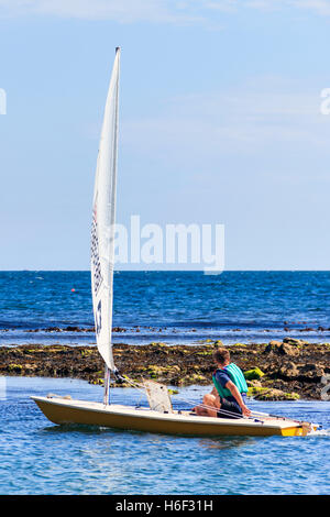 Eine einzige Segler segeln auf einem ruhigen See bei Ringstead Bay, Dorset, England, Großbritannien Stockfoto