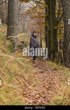 Eine glamouröse Frau Wandern durch die Wälder im Herbst fallen Saison einen Hut lässig Wolle Poncho Freizeit Verschleiß wollig zu Fuß o