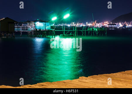 Holzhaus und Holzbrücke am Meer in der Nacht mit Farblicht Stockfoto