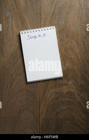Dinge auf Notizblock auf Holztisch Aufgabenliste Stockfoto