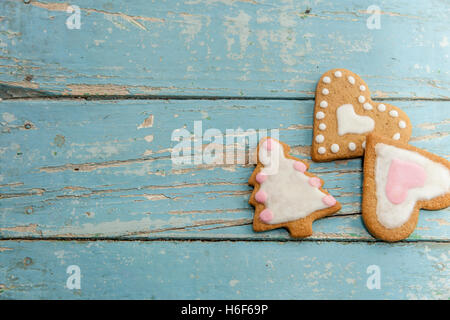 Winter-Lebkuchen mit handgefertigten Sahnehäubchen auf einem blauen Holztisch. Herzförmige, sternförmigen und Weihnachtsbaum geformt. Stockfoto