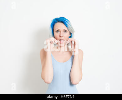 Junge schöne blaue Haare alternative Hipster Frau betäubt Ausdruck Blick in die Kamera mit der Hand den Mund auf weiße Rückseite Stockfoto