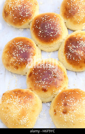 Frisch zubereitete, hausgemachte Burger-Brötchen auf einem Alu-Blech mit Backpapier abgedeckt. Stockfoto