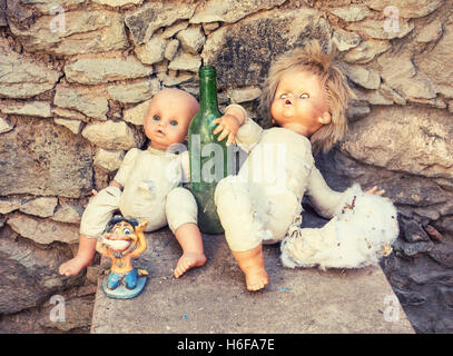 Zwei alte Puppen gegen leere Weinflasche in verlassenen Berg Haus nächste Schmiere Rauchen Abbildung gestützt Stockfoto