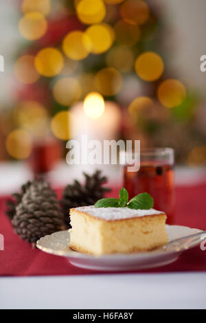 Käsekuchen und Weihnachtsbaum im Hintergrund Stockfoto