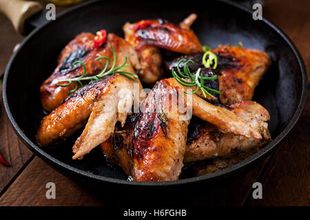 Gebackene Hähnchenflügel in Pfanne auf Holztisch. Stockfoto