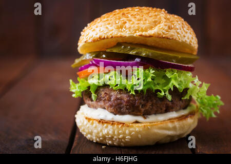 Big Sandwich - Hamburger Burger mit Rindfleisch, Gurken, Tomaten und Tartar sauce auf hölzernen Hintergrund. Stockfoto
