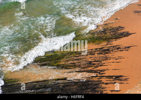 Draufsicht auf Felsformationen auf Monte Clerigo Strand und Surf-Welle mit Schaum (Aljezur, Algarve, Portugal). Stockfoto