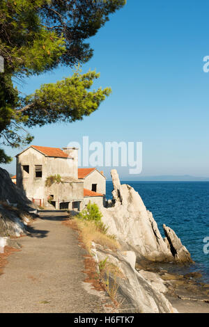 Ein verlassener Gebäude auf Felsen am Rand Wassers durch das Meer in Trpanj Kroatien Stockfoto