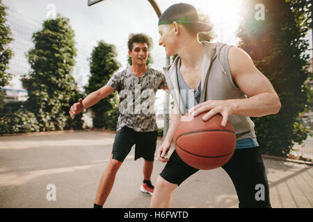 Zwei junge Freunde, Basketball auf Platz im Freien zu spielen und Spaß haben. Streetball Spieler mit einem Basketball-Spiel. Stockfoto