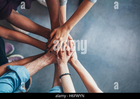 Draufsicht der jungen Menschen, die ihre Hände Zusammenstellung hautnah. Freunde mit Stapel der Hände zeigen Einigkeit und Teamarbeit. Stockfoto